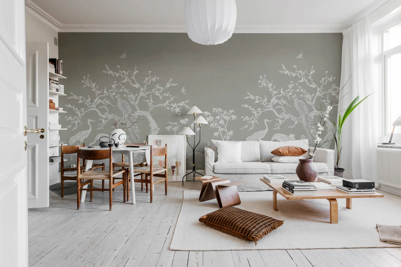 Bright living room with a panoramic blossom and heron mural covering the full wall behind a pale sofa